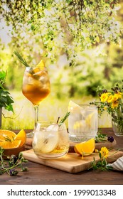Three colorful summer cocktails on the table. Hard seltzer cocktails with various fruits: pear, orange and lemon. Summer party table outdoor in a house backyard with сold summer drinks. 