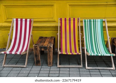 Three colorful sun loungers and a wooden table outside