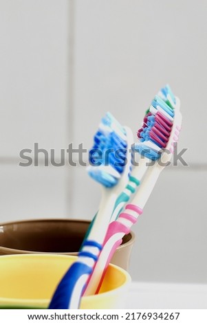 three colorful toothbrushes in colorful mugs on the bathroom table. High quality photo