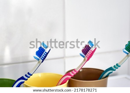 three colorful toothbrushes in colorful mugs on the bathroom table. High quality photo