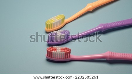 Three colorful toothbrushes with plastic handle on blue background isolated