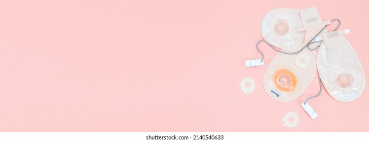 Three colostomy bags with clothespins lie on the right side on a pale pink