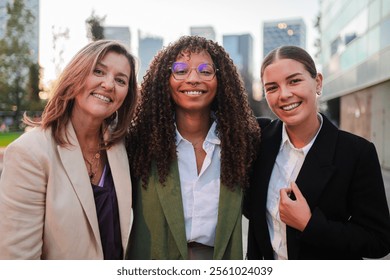 Three confident businesswomen smiling looking at camera. Teamwork, diversity, professionalism, and success while standing together outdoors, radiating, happiness and positive energy in the workplace - Powered by Shutterstock