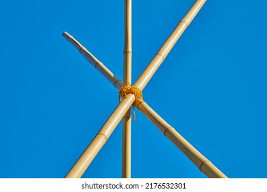 Three connected bamboo poles protrude into the blue sky and hold each other.