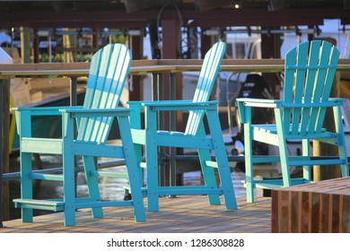 Three Cool Turquoise Painted Coastal Lounge Beach Chairs On The Dock At A Local Island Hangout. 