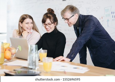 Three Coworkers Talking To Boss Over Video Call In The Office. Businessman And Two Businesswomen Using Laptop To Talk To Their Superior.