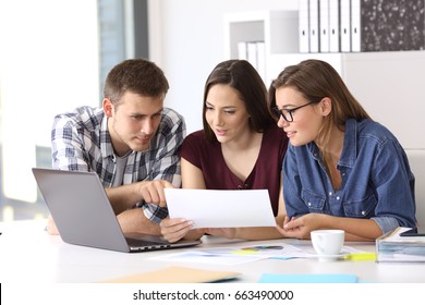 Three coworkers working at office comparing data with laptop and documents
