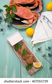 Three Crab Cakes Appetizer With Spicy Sauce And Fresh Parsley. Dungeness Crab In The Background.
