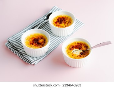 Three Creme Brûlées With A Cracked Top And Spoon Digging In