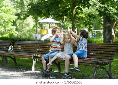 drei süße Geschwister auf einer Parkbank