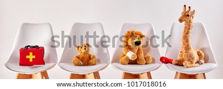 Three cute stuffed animal toys on chairs in the waiting room of a modern hospital or health center for children