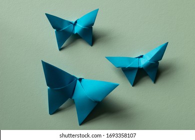 Three cyan blue origami butterflies on a seafoam green background with shadow. Arkivfotografi