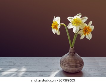 Three daffodils in a small vase on a dark background - Shutterstock ID 637399603