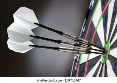 Three Darts In Bullseye Of Dartboard
