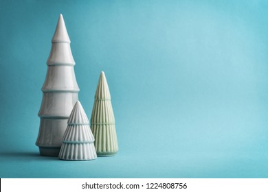 Three decorative ceramic christmas tree on light blue background closeup