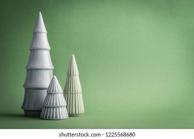 Three decorative ceramic christmas tree on light green background closeup