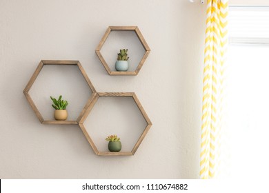 Three decorative wooden, floating, hexagon wall shelves, with decorative plants