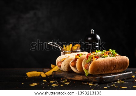 Three delicious hotdogs on dark wood background