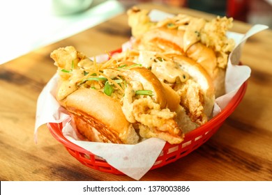 Three delicious sandwiches with fried shrimp, cucumber, carrot and sauce on the red plate and wooden table. Fresh and tasty shrimp roll, seafood meal. Fancy street food concept. - Image