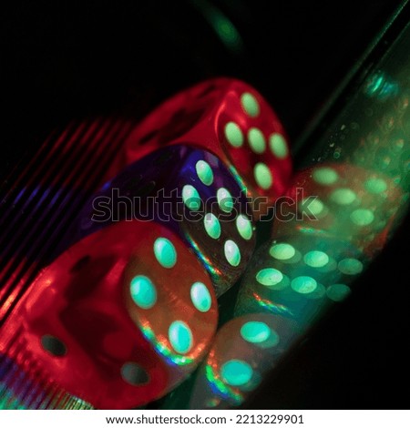 Three dice next to their reflection covered by a multi-colored light