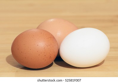 Three different color eggs (white, brown and pinkish-brown) isolated on wood table