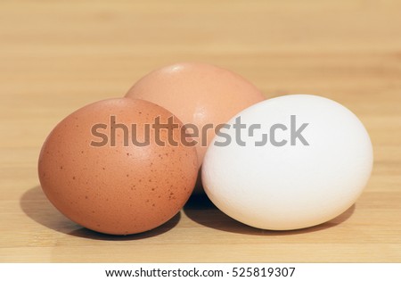 Three different color eggs (white, brown and pinkish-brown) isolated on wood table