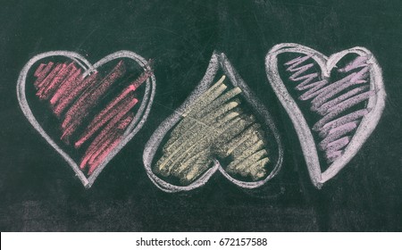 Three different colored hearts on chalkboard, blackboard texture