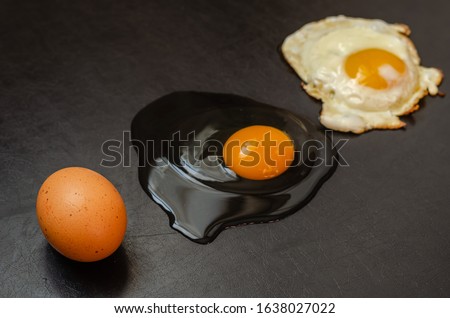 Three different conditions of one chicken egg on a black background. Lined line of whole chicken egg, raw broken and fried eggs. Side view. Selective focus. Close-up.