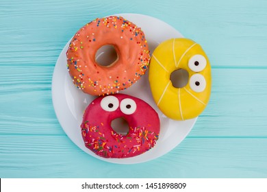 Three Different Donuts On Plate. Funny Glazed Doughnuts On Blue Wooden Background, Top View. Yummy Sweets In Pastry Shop.