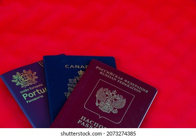 Three different passports isolated on red background. Canadian, Portuguese and Russian passports for entry in different countries