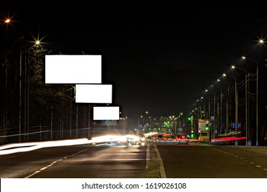 Three Different Sized Blank Billboards Above The Roadway At Night.