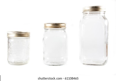 Three different sized glass mason jars for canning in line on a white isolated background.