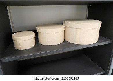 Three Different Sizes Of Broken White Round Boxes In Black Shelving Unit