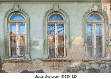 three dilapidated windows on the old hobbled home