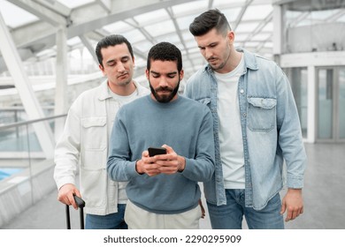 Three Discontented Tourists Guys Using Phone Having Issue Booking Tickets Online In App Standing With Suitcase In Modern Airport Inside. Male Passengers Having Problems With Connection - Shutterstock ID 2290295909