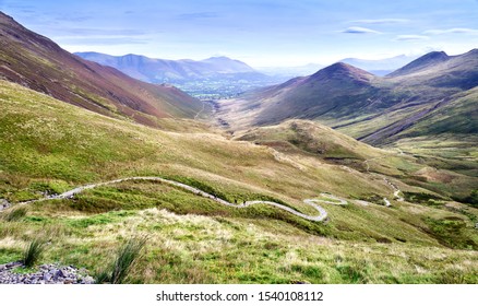 Three Distant Hikers Walking Up A Winding Rocky Path From Coledale Beck That Leads To Hopegill Head, Crag Hill And Grasmoor In The Lake District.