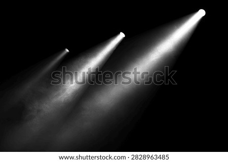 Three distinct beams of white light cut through a smoky atmosphere, originating from off-camera and projecting upwards and to the right against a pure black background.