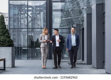 Three Diverse Business People Walking And Talking Focused And Thoughtful Seriously Outside Office Building, Male And Female, Discussing Plans And Work Project