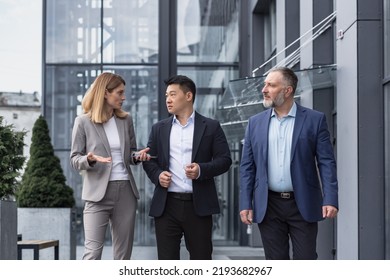 Three Diverse Business People Walking And Talking Focused And Thoughtful Seriously Outside Office Building, Male And Female, Discussing Plans And Work Project