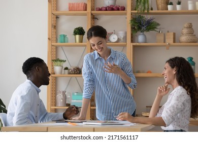 Three diverse cheerful colleagues have fun distracted from work, joke at workplace gather in office for project discussion, collaborative task analysis. Teamwork, friendly teammates workflow concept