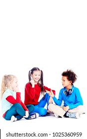 Three Diverse Elementary Students Sitting On Floor And Playing Rock Paper Scissors Game