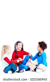 Three Diverse Elementary Students Sitting On Floor And Playing Rock Paper Scissors Game