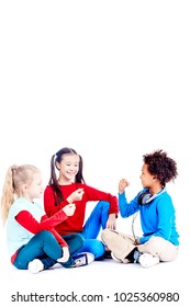 Three Diverse Elementary Students Sitting On Floor And Playing Rock Paper Scissors Game