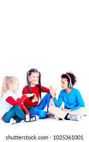 Three Diverse Elementary Students Sitting On Floor And Playing Rock Paper Scissors Game