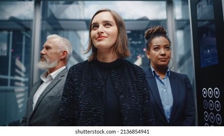 Three Diverse Multiethnic International People Ride a Glass Elevator to Office in a Modern Business Center. Focus on a Happy Young Beautiful Businesswoman Standing in Front in a Lift. - Powered by Shutterstock