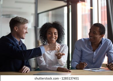 Three diverse people gathered in real estate agency, signing lease agreement afro woman receiving keys from first dwelling new home, realtor giving keys to female client after making a property deal - Powered by Shutterstock