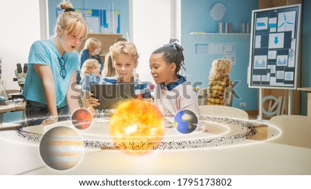 Three Diverse School Children in Science Class Use Digital Tablet Computer with Augmented Reality Software, Looking at Educational 3D Animation Of Solar System. VFX, Special Effects Render Stockfoto © 