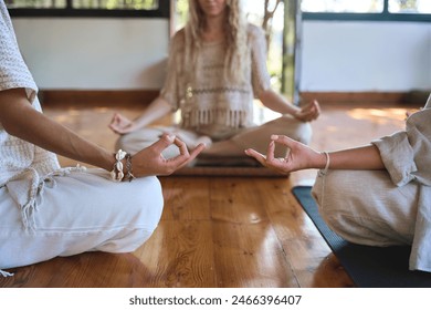 Three diverse women meditating sitting together in yoga poses at body care yoga training. Women group doing yoga breathing exercises during holistic healing session. Close up view retreat background. - Powered by Shutterstock