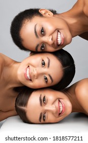 Three Diverse Women With Perfect Faces And Skin Posing Together Smiling To Camera On Gray Background. Multicultural Beauty Concept. Vertical