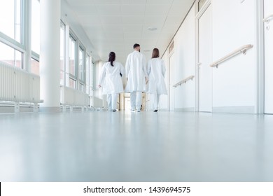 Three doctors walking down a corridor in hospital seen from behind